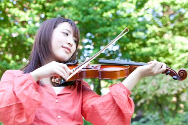 Genç Asyalı kadın yazın keman çalıyor.