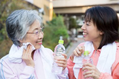İki Asyalı kadın açık havada su içiyor.