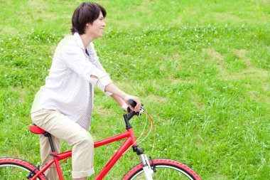 Bisiklet süren Asyalı adam.