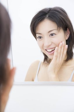 Tuvalette yüz kremi süren bir kadın. 