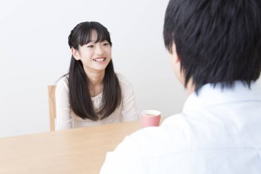 Genç baba ve kızı ellerinde fincanlarla masada oturuyorlar. 