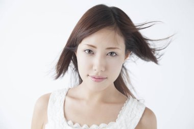 Asyalı güzel genç kadın beyaz arka planda kameraya bakıyor.