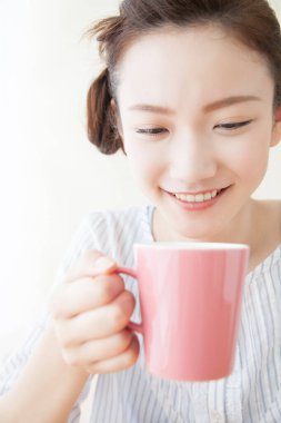 Genç Asyalı kadın kahve içiyor.