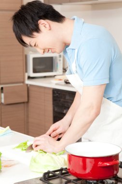 Genç adam mutfakta yemek hazırlıyor.