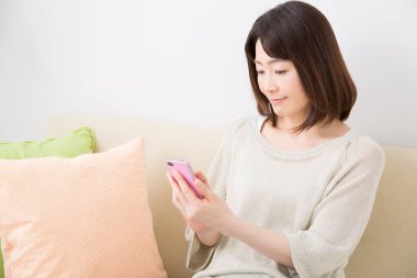 Kadın evde cep telefonu kullanıyor. 