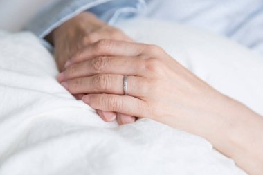 Yaşlı kadın ellerini battaniyeye koy.