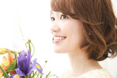 Bir buket taze çiçekle gülümseyen genç Japon kadın.