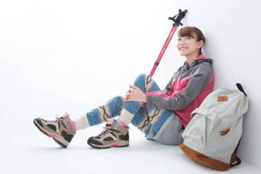 İskandinav bastonlarıyla gülümseyen Japon kadın yürüyüşçünün stüdyo portresi.