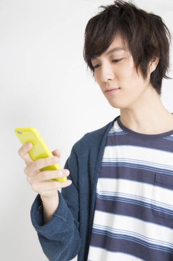 Genç Asyalı öğrenci cep telefonu kullanıyor.