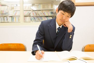 Sınıftaki masanın üzerine yazan Japon öğrenci.