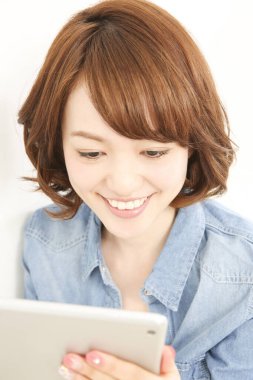 Gülümseyen ve dijital tablet kullanan güzel Japon kadının portresi.