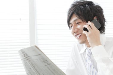 Ofiste telefon kullanan Asyalı bir adam var.