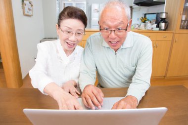 Mutfakta dizüstü bilgisayar kullanan yaşlı çift.