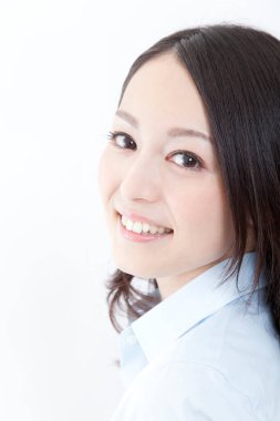 Genç bir kadın beyaz arka planda kameraya bakıyor.