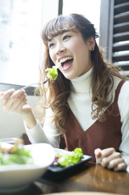 Güzel Asyalı kadın kafede sağlıklı bir öğle yemeği yiyor.