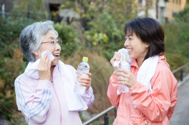Eğitimden sonra elinde şişe su olan iki Asyalı kadın.