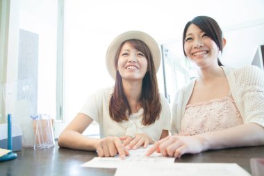 Masada oturan iki gülümseyen kadın.