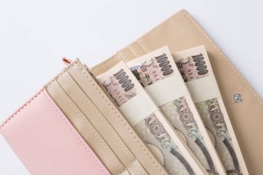 Japon banknotlarıyla dolu pembe kadın cüzdanı. Beyaz arka planda. 