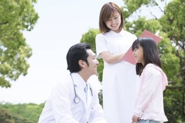 Doktor ve hemşire dışarıdaki gülümseyen kızla etkileşim halindeler.