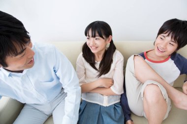 Genç Asyalı aile kanepede dinleniyor.