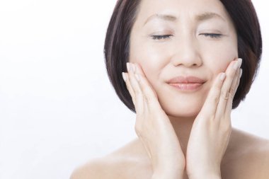 Asyalı kadın yanaklarına dokunuyor. 