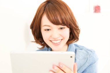 Dijital tablet kullanan gülümseyen Asyalı kadın