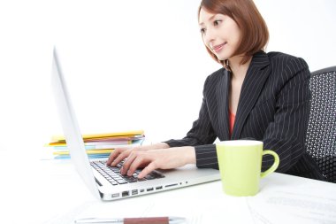 Masasında dizüstü bilgisayarı olan genç Asyalı iş kadını. 