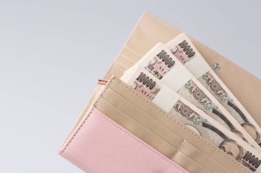 Japon banknotlarıyla dolu pembe kadın cüzdanı. Beyaz arka planda. 