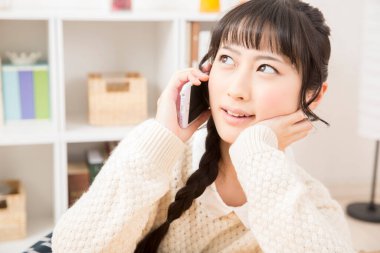 Güzel Asyalı genç bir kadın telefonda konuşuyor.