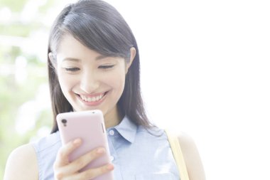 Parkta akıllı telefon kullanan genç kadın. 