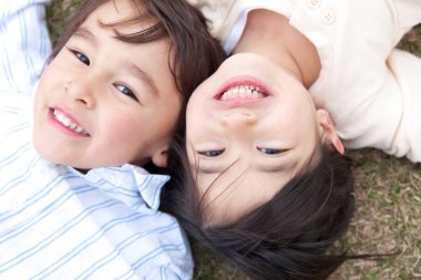 Çimlere uzanmış iki çocuğun portresi.