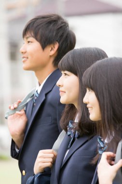 Aynı üniformayı giyen bir grup öğrenci okullarında birlikte dikiliyorlar.