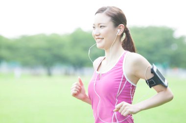 Genç Asyalı kadın koşucu pistte koşuyor.