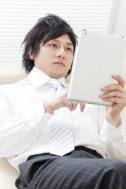 Evde tablet üzerinde çalışan adam