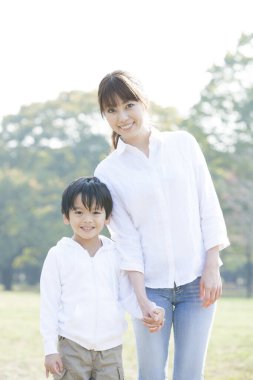 Oğluyla parkta yürüyen Asyalı genç bir kadın.