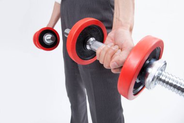 Adamın elleri beyaz arka planda dambılları tutuyor.