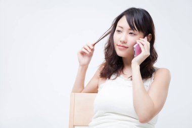 Beyaz arka planda akıllı telefon kullanan güzel Asyalı bir kadının portresi.