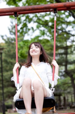 Kadın parkta salıncakta sallanıyor