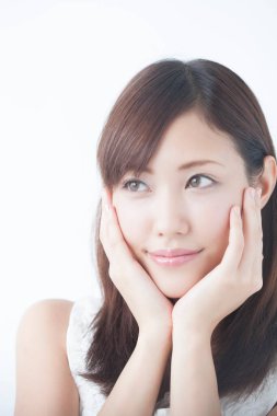 Genç, güzel Asyalı bir kadın. Yüzü asık, soyutlanmış arka planda poz veriyor.  