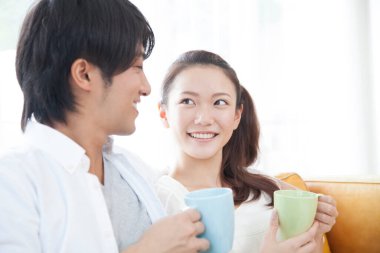 Genç Asyalı çift evde kahve içiyor.