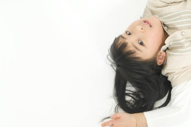 Beyaz zeminde yatan Asyalı küçük kız.