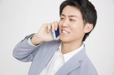 Genç Asyalı iş adamı izole edilmiş arka planda cep telefonu kullanıyor