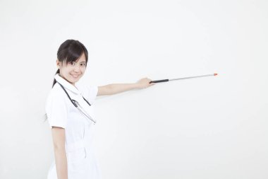 Asyalı kadın doktor beyaz arka planda işaretli bir şeye işaret ediyor. 