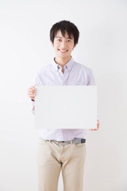 Asyalı adam beyaz boş levha tutuyor.