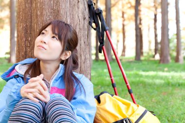 Sarı sırt çantalı genç Japon kadın sonbahar parkında yürüyüş yapıyor.