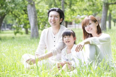 Genç Asyalı aile parkta dinleniyor. 