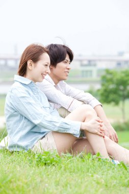 Asyalı çift çimlerin üzerinde oturuyor.