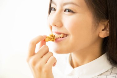 Güzel Asyalı genç kadın evde patlamış mısır yiyor.