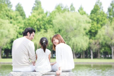 Mutlu Japon ailesinin portresi yaz parkında dinleniyor.