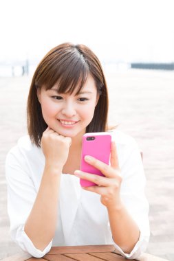 Genç Japon kadın dışarıda akıllı telefon kullanıyor.